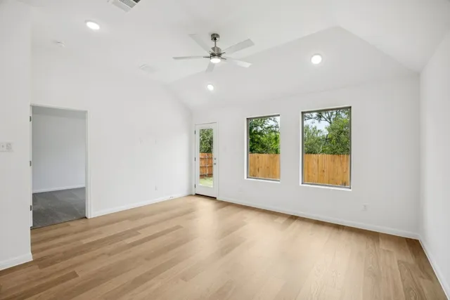 an empty room with wooden floor and windows