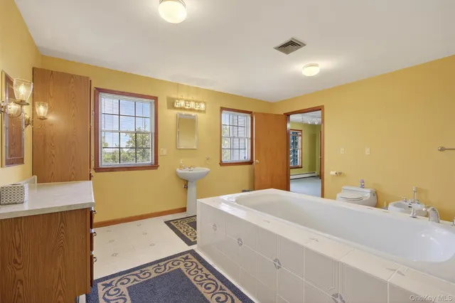 a spacious bedroom with a bed and a dresser next to a window