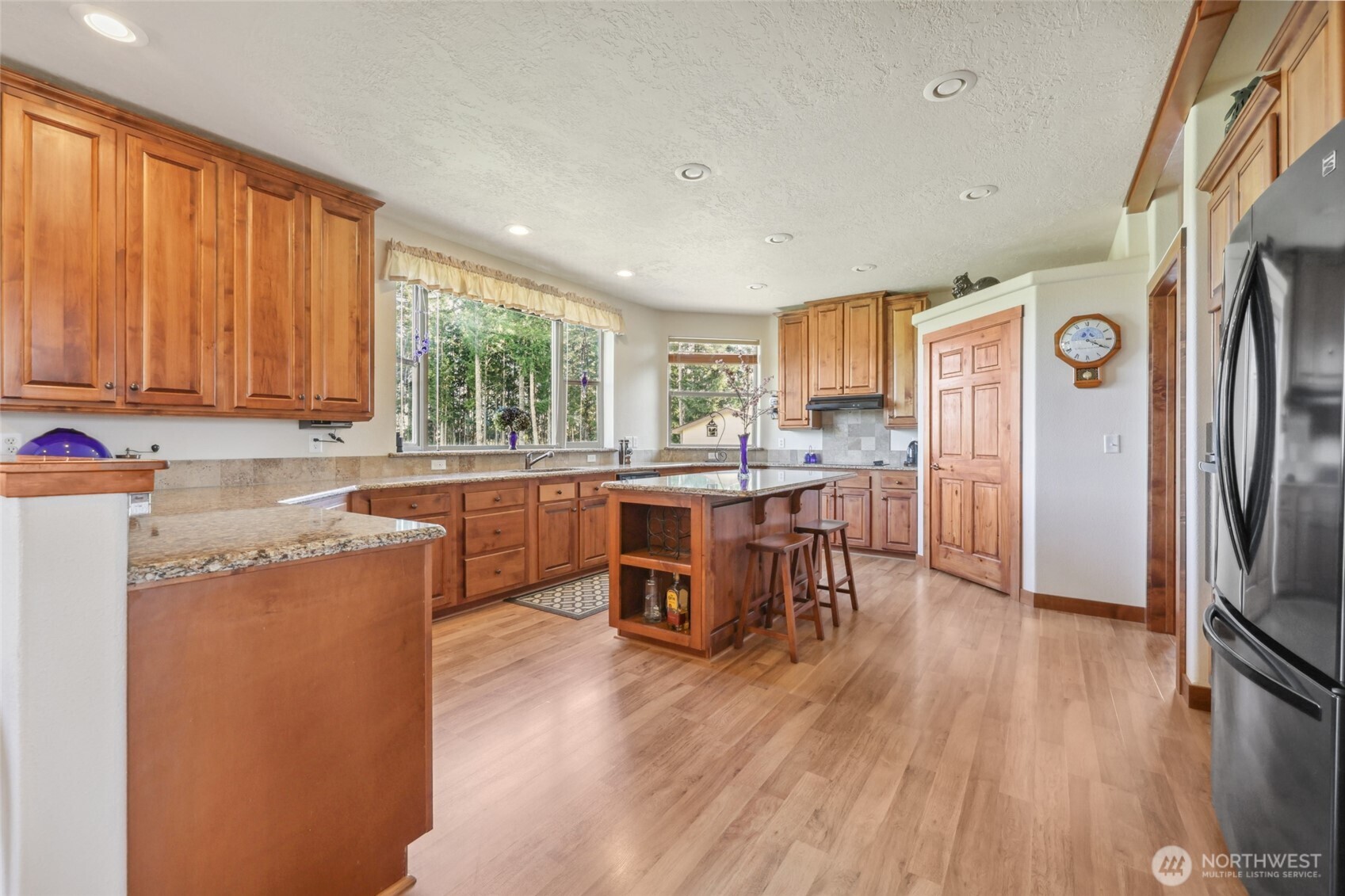 12245 Langworthy Road Southwest Rochester, WA 98579 - Photo 13 of 39 a kitchen with stainless steel appliances granite countertop a refrigerator a sink dishwasher a stove and a dining table with wooden floor