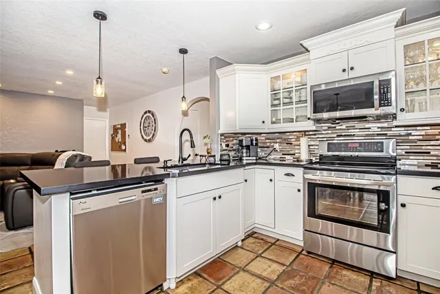a kitchen with stainless steel appliances a stove a sink and white cabinets with wooden floor