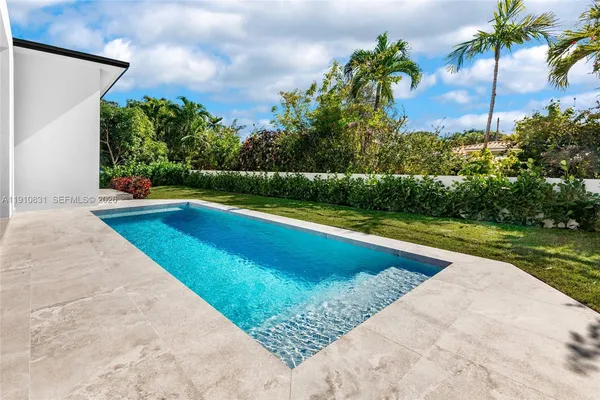 a view of swimming pool with a yard and palm trees