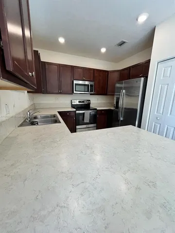 a kitchen with stainless steel appliances a refrigerator sink and microwave