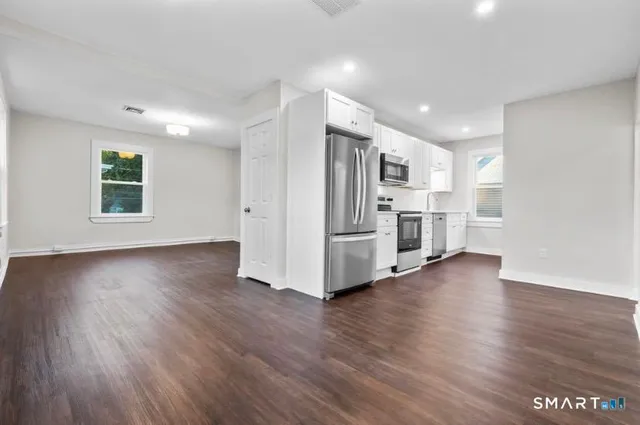 a view of a kitchen with a fridge wooden floor and a window