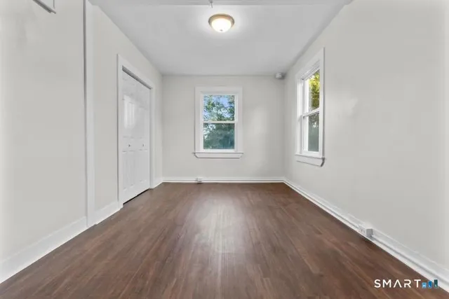 an empty room with wooden floor and windows