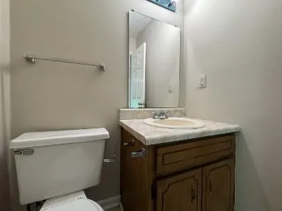 a bathroom with a granite countertop toilet sink and mirror