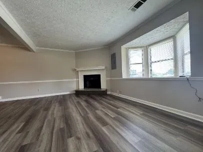 an empty room with wooden floor fireplace and windows
