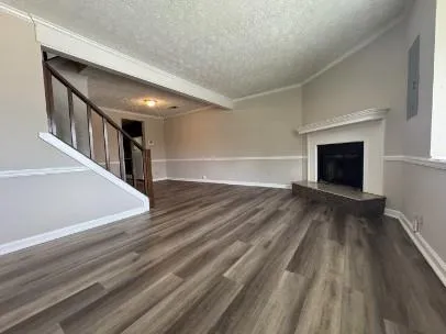 a view of an empty room with wooden floor fireplace and a window