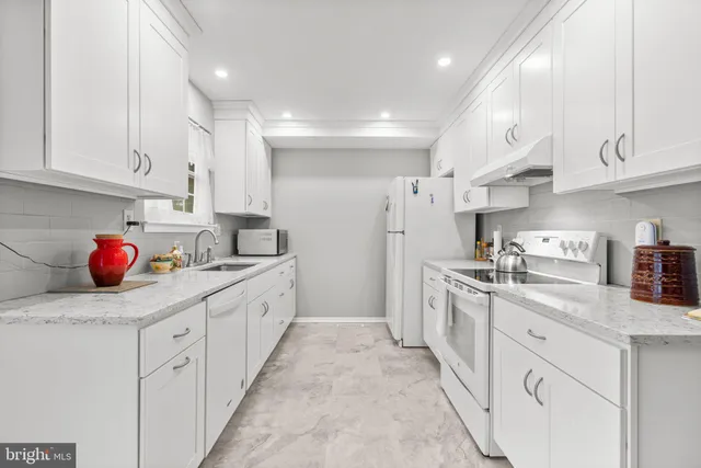 a kitchen with white cabinets and sink