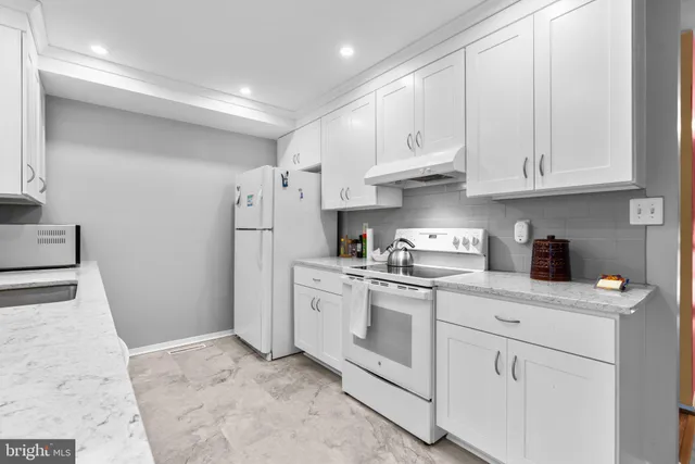 a kitchen with white cabinets and white appliances