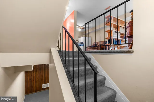 a view of staircase with lots of frames on wall and a window