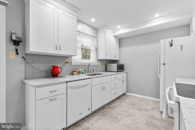 a kitchen with granite countertop white cabinets and white appliances
