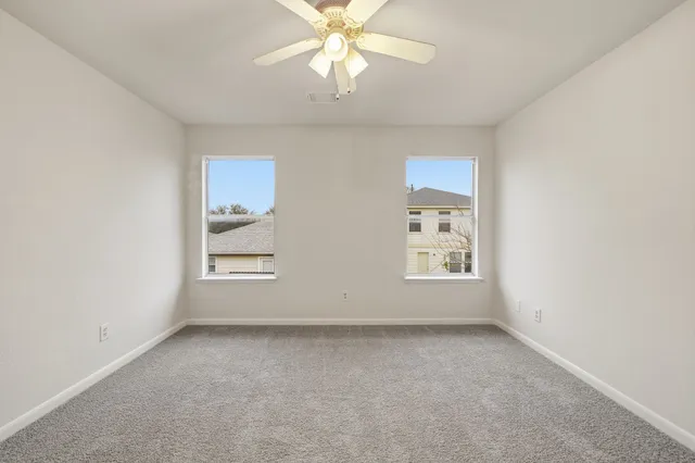 an empty room with a window and ceiling fan