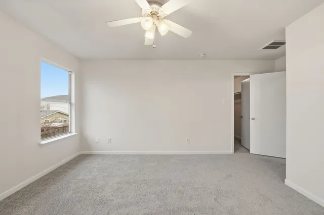 an empty room with windows and fan