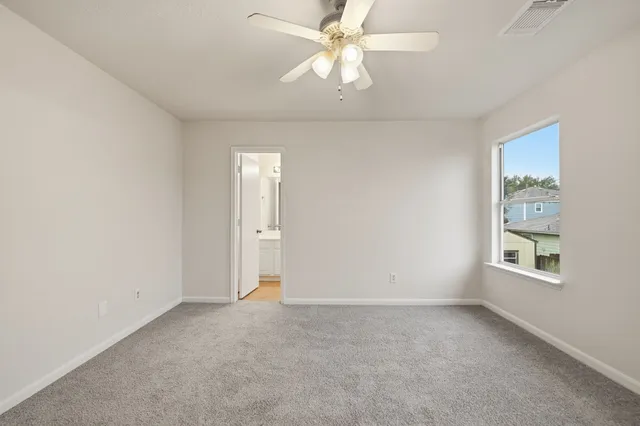 an empty room with a chandelier fan and windows