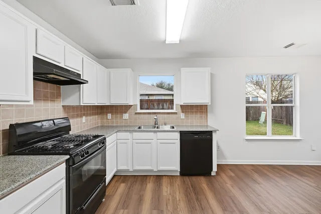 a kitchen with a sink stove top oven and cabinets