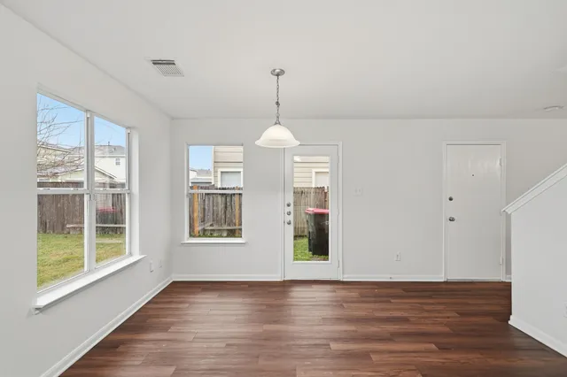 a view of an empty room with window and wooden floor