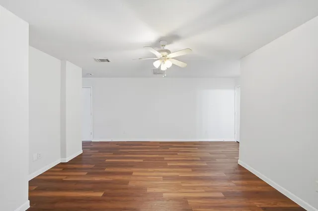 a view of a room with wooden floor and a ceiling fan