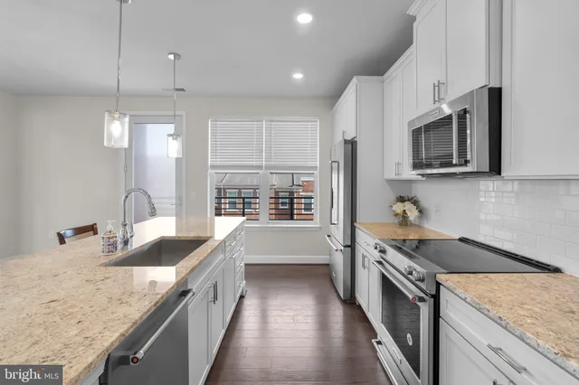 a kitchen with stainless steel appliances granite countertop a sink stove and refrigerator