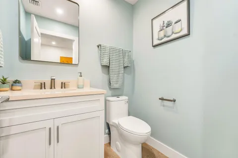 a bathroom with a toilet sink vanity and mirror
