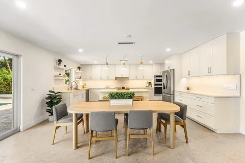 a kitchen with kitchen island a dining table and chairs