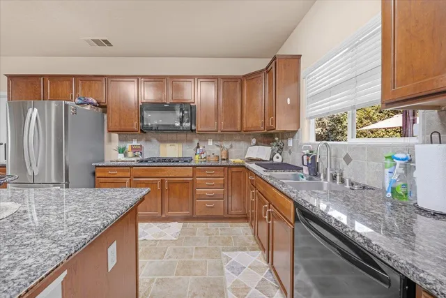 a kitchen with stainless steel appliances granite countertop a sink stove and refrigerator