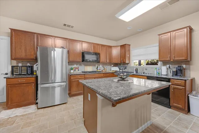 a kitchen with stainless steel appliances granite countertop a refrigerator stove and sink