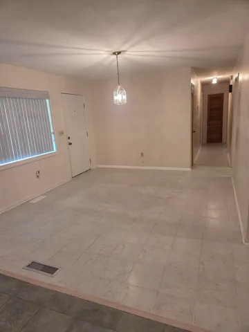 an empty room with chandelier fan and windows