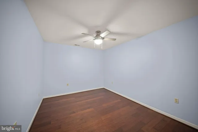 an empty room with a chandelier fan and windows