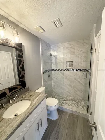 a bathroom with a granite countertop sink toilet a mirror and shower