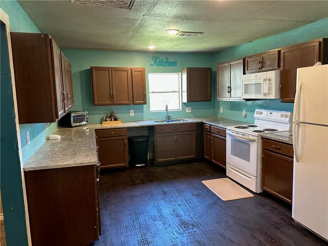 a kitchen with a refrigerator a stove top oven a sink dishwasher and wooden floor