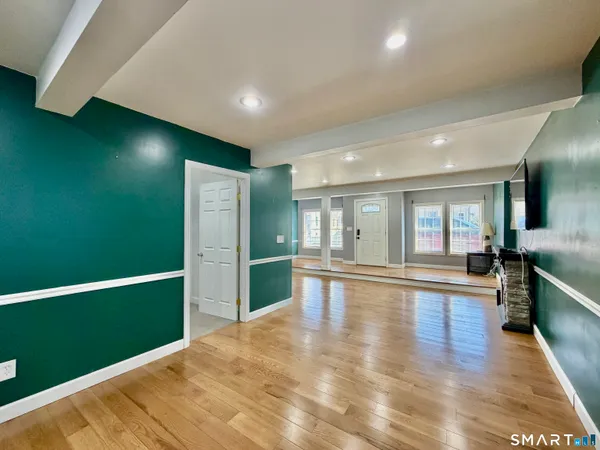 a kitchen with stainless steel appliances granite countertop a refrigerator a sink dishwasher a stove and a dining table with wooden floor