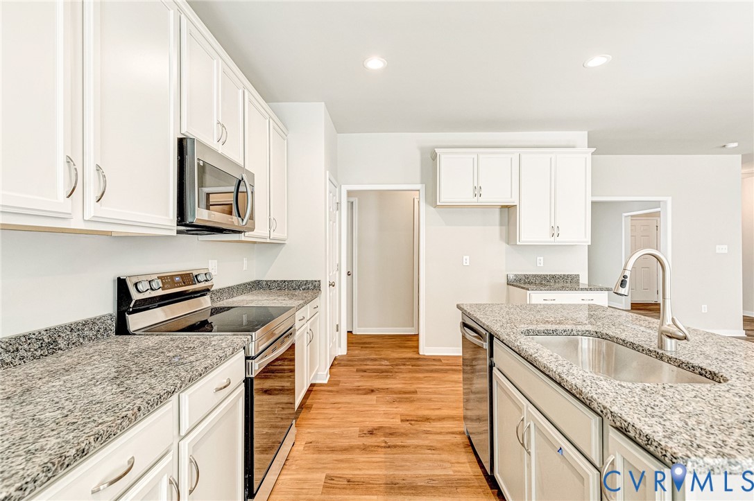 8355 Patrick Henry Boulevard Mechanicsville, VA 23116 - Photo 18 of 48 a kitchen with granite countertop a sink a stove and a wooden floors