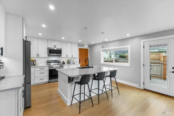 a kitchen with stainless steel appliances kitchen island granite countertop a stove a refrigerator a sink a dining table and chairs with wooden floor