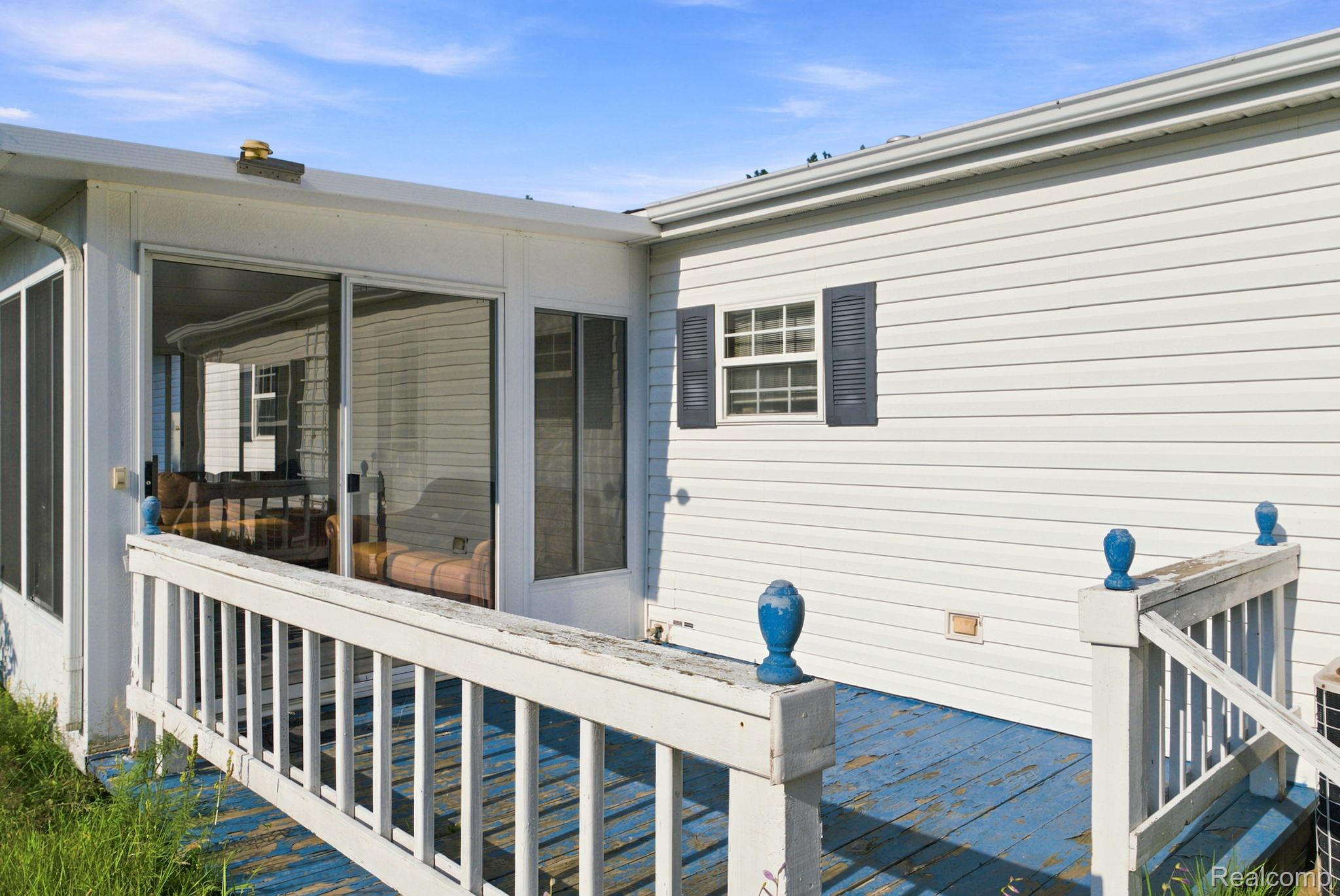 2390 Lakeshore Road Applegate, MI 48401 - Photo 83 of 97 Sliding glass door entry, white vinyl siding, exterior window with shutters, wooden deck with railing, and blue-painted deck floor
