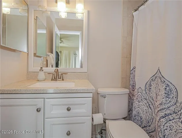 a bathroom with a granite countertop toilet sink and mirror