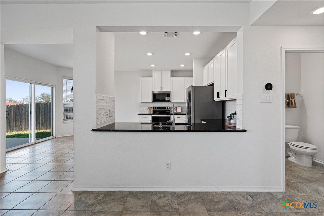 204 Benmyrtle Trail Georgetown, TX 78626 - Photo 11 of 35 a large white kitchen with kitchen island a sink a counter and a fireplace