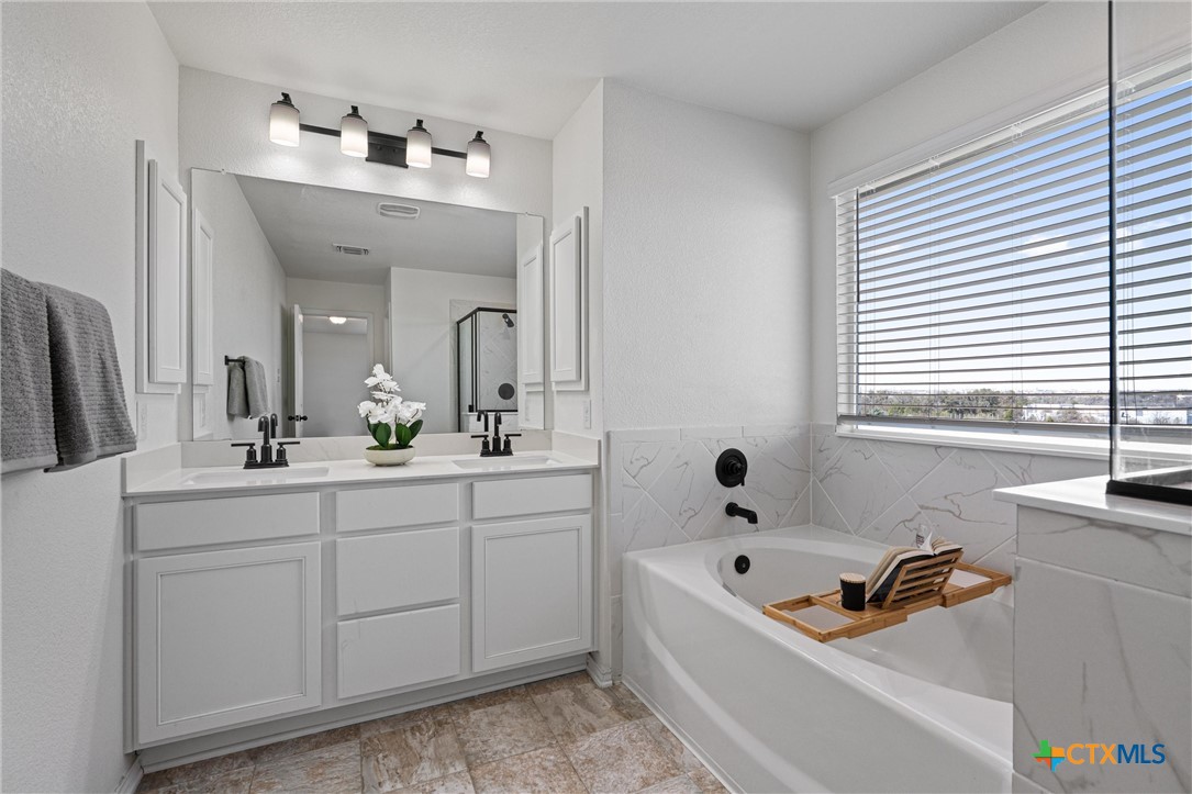 204 Benmyrtle Trail Georgetown, TX 78626 - Photo 23 of 35 a bathroom with a tub a double vanity sink and mirror