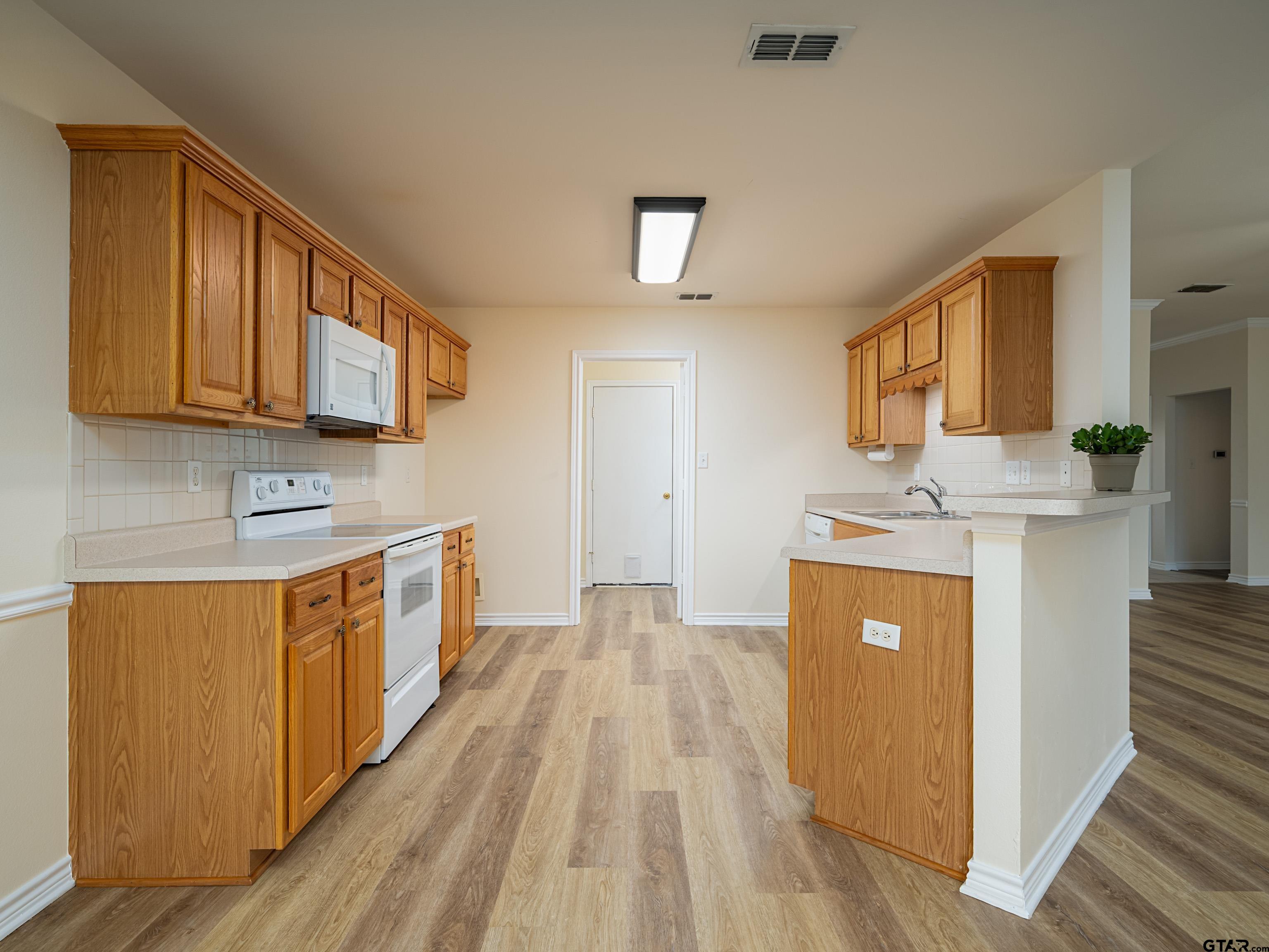 1521 Rice Road Tyler, TX 75703 - Photo 8 of 27 a kitchen with stainless steel appliances granite countertop a stove a sink dishwasher and a refrigerator with wooden floor