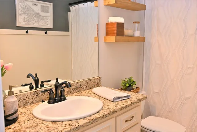 a bathroom with a granite countertop sink mirror and toilet