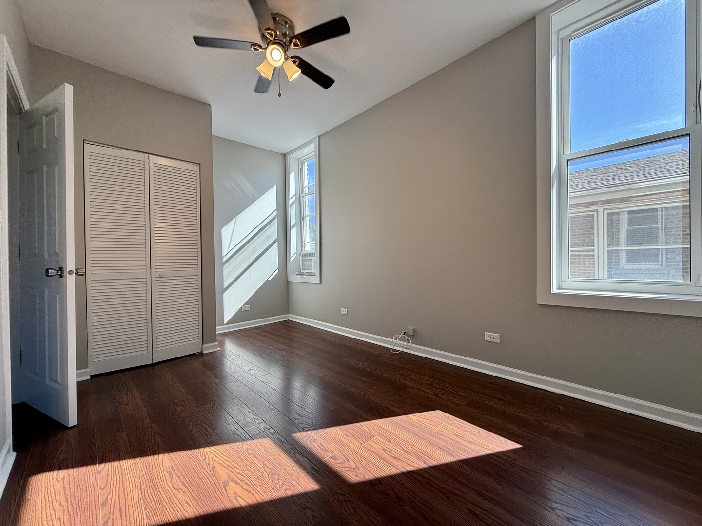 3235 South Racine Avenue, Unit 2M Chicago, IL 60608 - Photo 6 of 11 an empty room with wooden floor fan and windows
