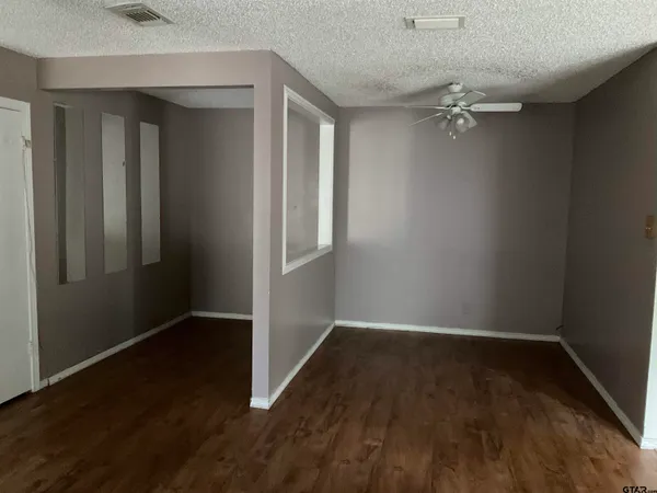an empty room with wooden floor closet and windows