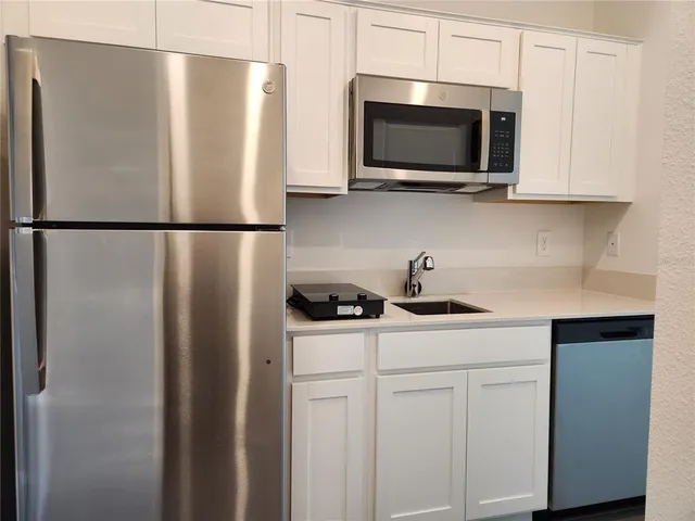 a kitchen with stainless steel appliances a refrigerator a microwave a sink and cabinets