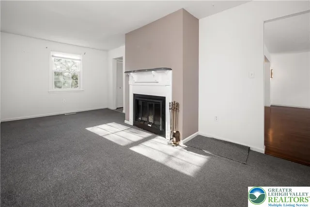 a view of an empty room with window and fire place