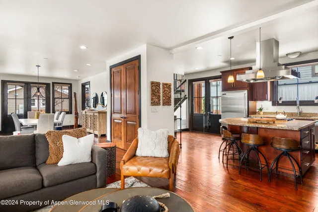 a kitchen with stainless steel appliances granite countertop a refrigerator a sink dishwasher a stove and a dining table with wooden floor