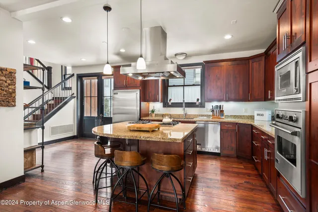 a kitchen with a stove a sink a dining table and chairs with wooden floor