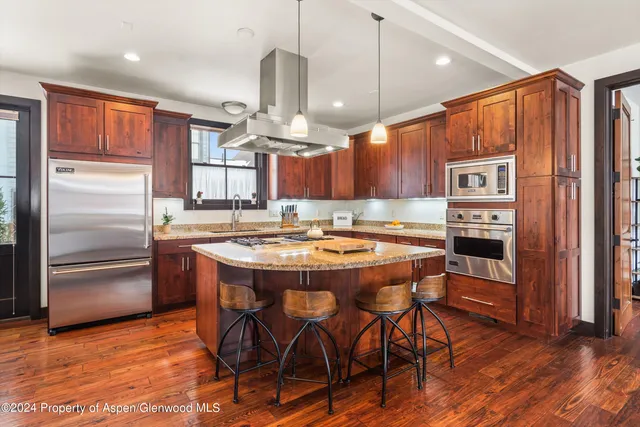 a kitchen with stainless steel appliances granite countertop a refrigerator a stove and a wooden floors