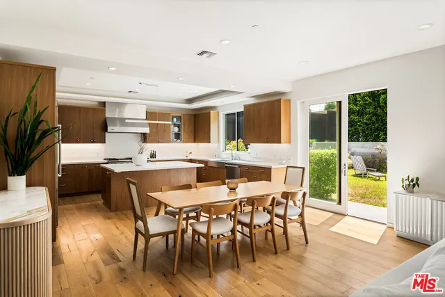 a dining hall with stainless steel appliances kitchen island granite countertop a dining table chairs and granite counter tops