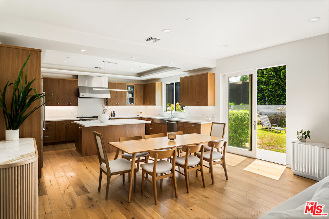 a dining hall with stainless steel appliances kitchen island granite countertop a dining table chairs and granite counter tops