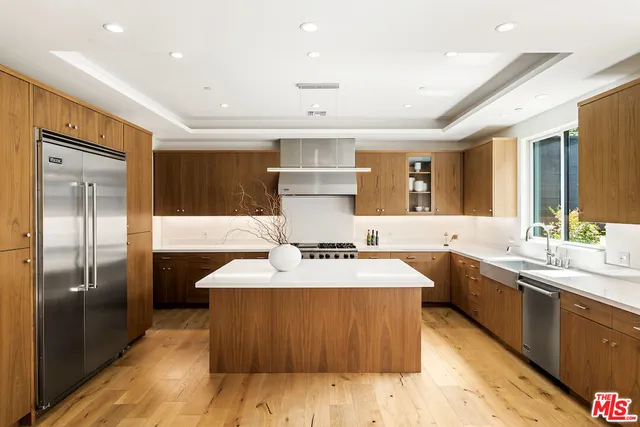 a large kitchen with a large counter top a sink stainless steel appliances and cabinets