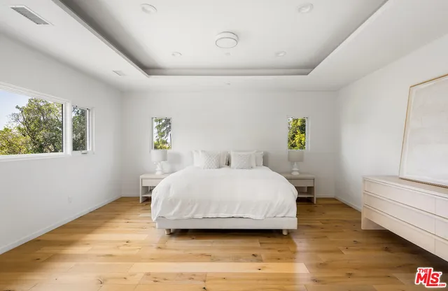 a spacious bedroom with a bed and wooden floor